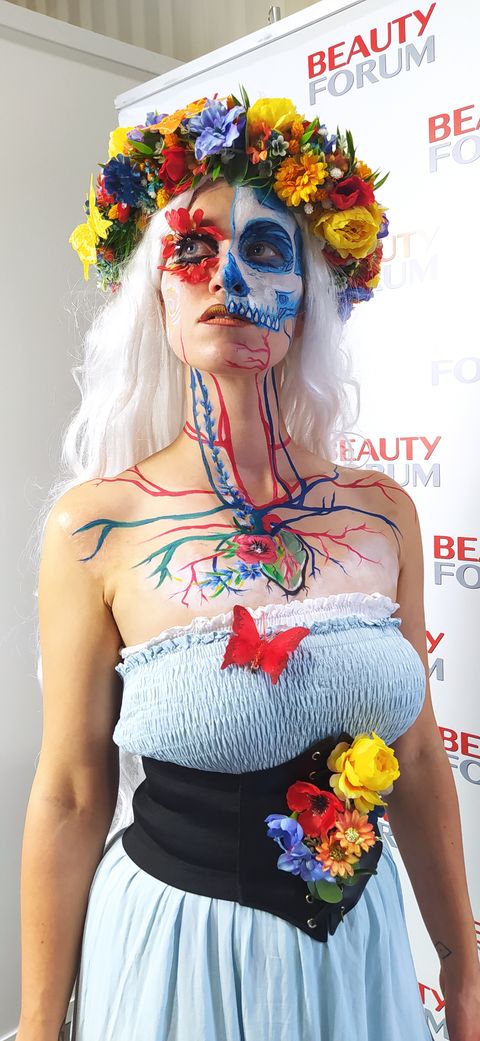 Bodypainting w stylu La Catrina – kobieta z malowaną twarzą czaszki i układem krwionośnym na klatce piersiowej, z kwiatową koroną na głowie. - pełna rozdzielczość