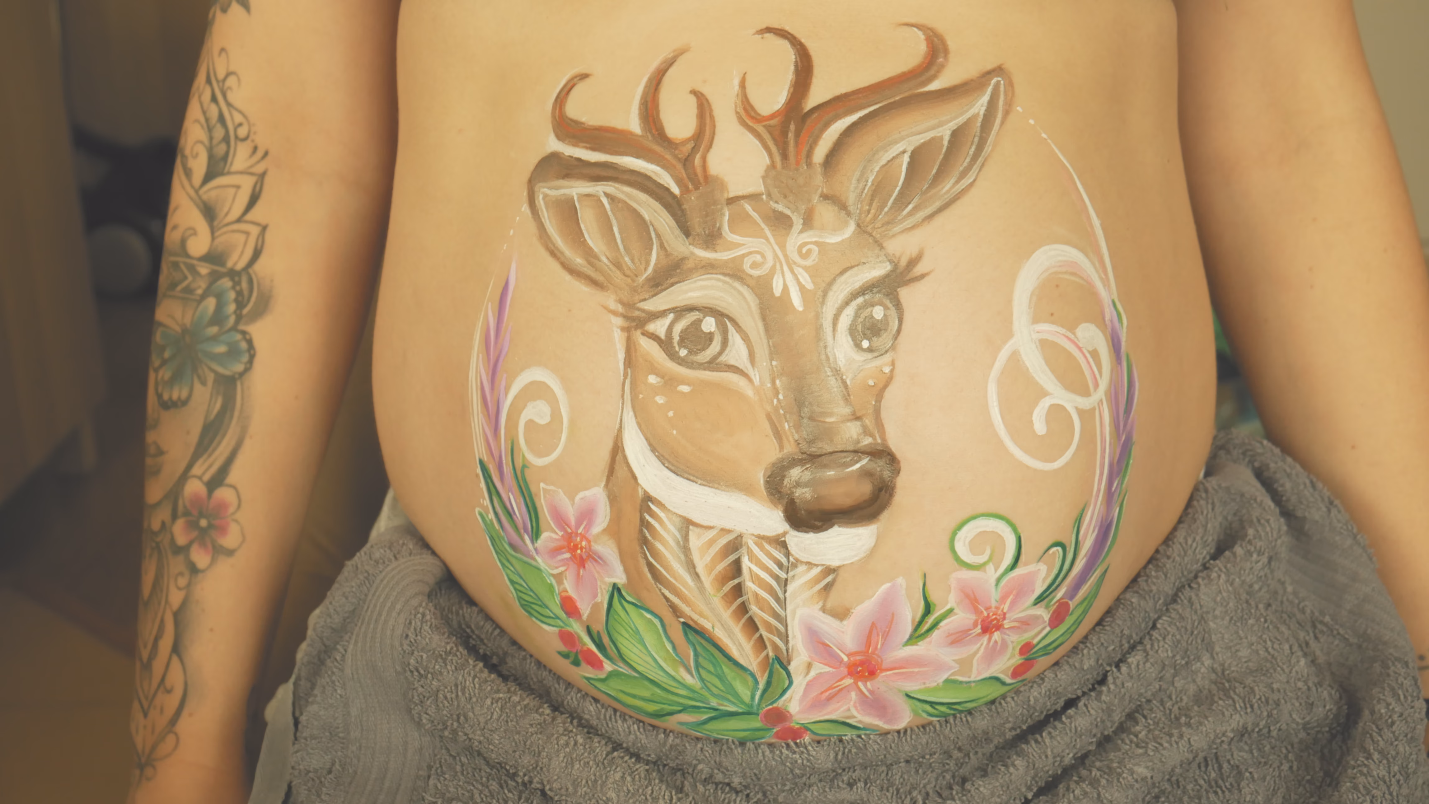 Pomalowany ciążowy brzuszek z wizerunkiem jelonka otoczonego kwiatami – symbol łagodności i nowego życia. Delikatny belly painting w pastelowych barwach, inspirowany naturą i macierzyństwem. - Lubin, Wrocław, Brzeg, Opole, Oława, Legnica - zoptymalizowana wersja do szybkiego ładowania